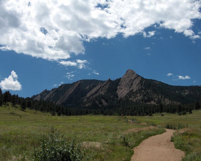 Trail through a green meadow toward the Flatirons in Boulder