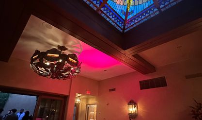 Pink-lit DJ booth under a stained glass skylight in a darkened hall