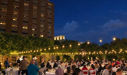 Guests at dinner tables under string lights at an outdoor evening reception