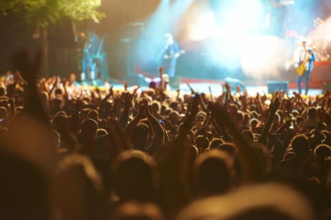 Crowd with raised hands in front of a lit concert stage