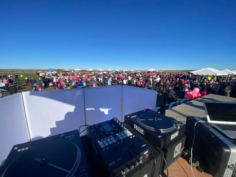 DJ turntables facing a large charity walk crowd dressed in pink