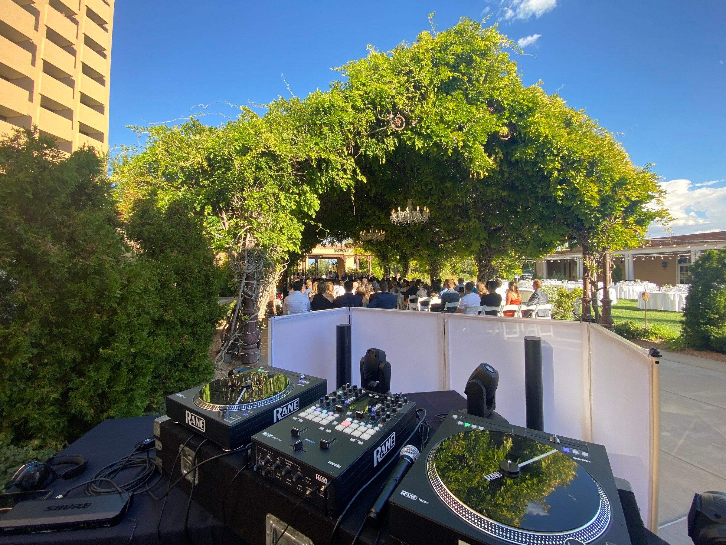 Beats Boutique DJ booth with Rane turntables set up beside a garden wedding ceremony