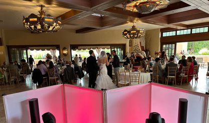 View from behind the DJ booth of a bride and groom greeting guests at their reception