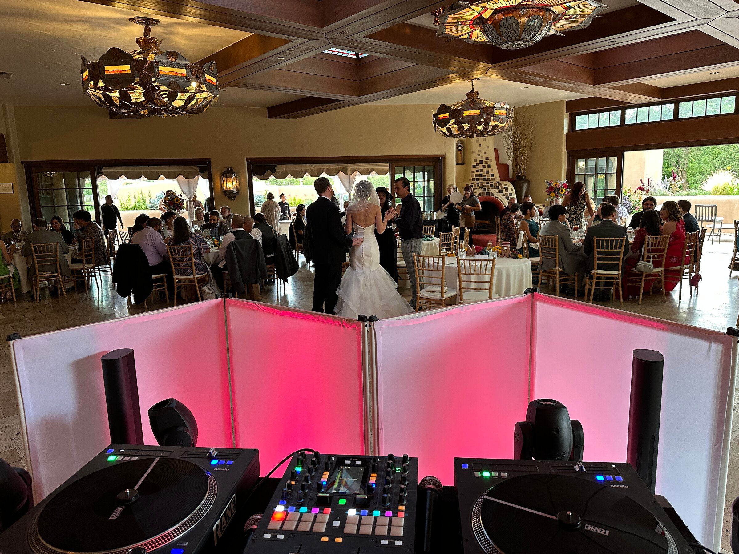 View from behind the DJ booth of a bride and groom greeting guests at their reception