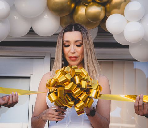 Grand opening ribbon cutting under a gold and white balloon garland