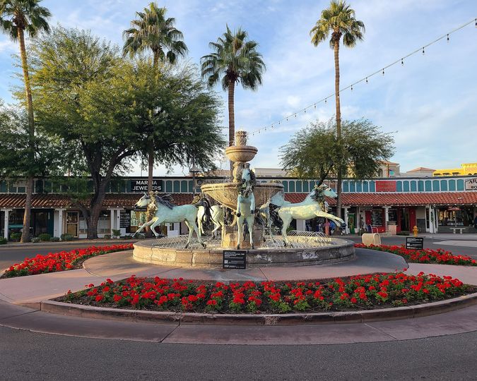 Bronze horse fountain ringed by red flowers and palms in Old Town Scottsdale