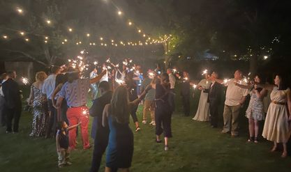 Guests lining a path with sparklers for a night-time send-off under string lights