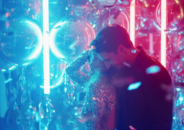 Couple dancing under neon lights and falling confetti