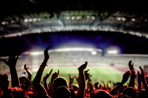 Fans cheering in a floodlit stadium